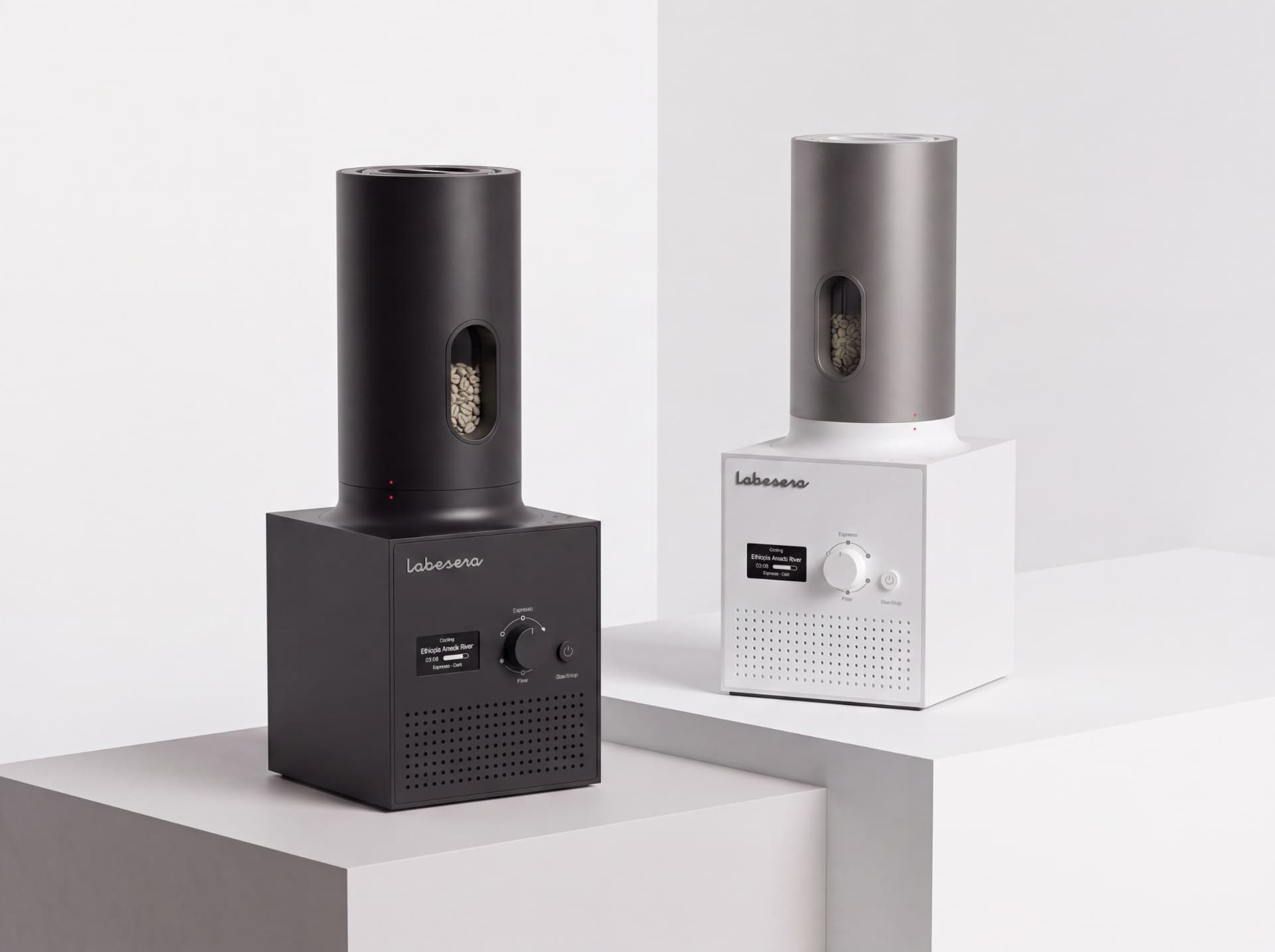 Two Labesera home coffee roasters, one black and one white, standing on studio pedestals